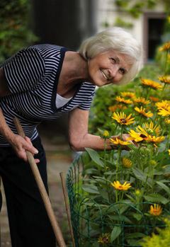 senior woman working in flower garden and smiling